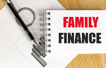 Family finance phrase on notepad with pen and financial graphs on wooden desk