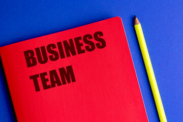 Business team title on red notebook with yellow pencil on blue background