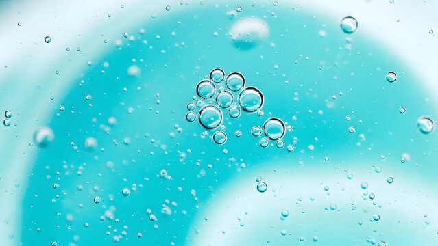 Numerous clear oxygen bubbles float suspended within a vibrant turquoise blue viscous liquid, creating an abstract and refreshing macro background texture perfect for science or cosmetic applications.