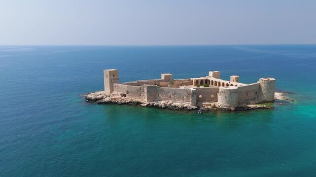 Kizkalesi, Mersin, Turkey. Maiden Castle island fortress completely surrounded by water, medieval architecture in mediterranean sea.. Aerial View, Departure of the camera