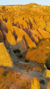 Vertical video. Goreme, Nevsehir, Turkey. Magical evening view of Devrent Valley with enchanting rock sculptures and warm sunset illumination.. Aerial View. Rich colors