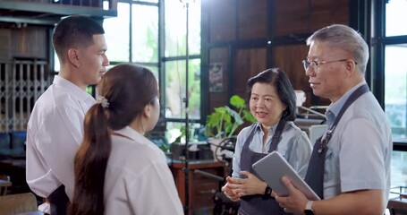 Elderly asian couple entrepreneurs encourage staff before opening cafe, teamwork collaboration builds confidence, husband wife share advice, motivate young employees deliver quality customer service - Powered by Adobe