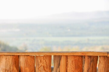 Wooden fence with natural texture in foreground and blurred rural landscape background, ideal for concepts of nature, countryside, copy space, and outdoor tranquility.