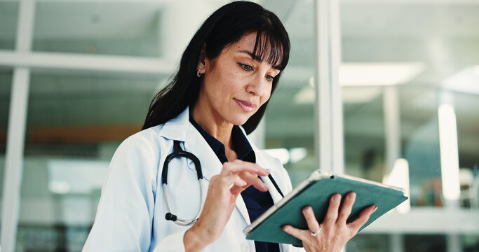 Woman, doctor and reading with tablet in hospital for research, medical report and confirm surgery. Surgeon, digital and browsing website for Telehealth, healthcare results and treatment information
