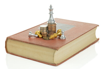 Chess king on stack of coins and book isolated on white background with clipping path.
