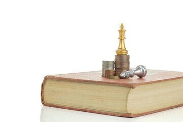 Stack of coins with chess pieces on book isolated on white background with clipping path.