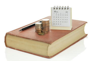 Coins with calendar and pen on book isolated on white background with clipping path.