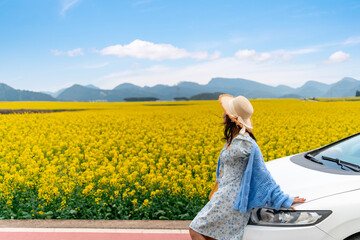 Happy young woman enjoying the canola fields while traveling to Luoping County in China, Road trip on vacation
