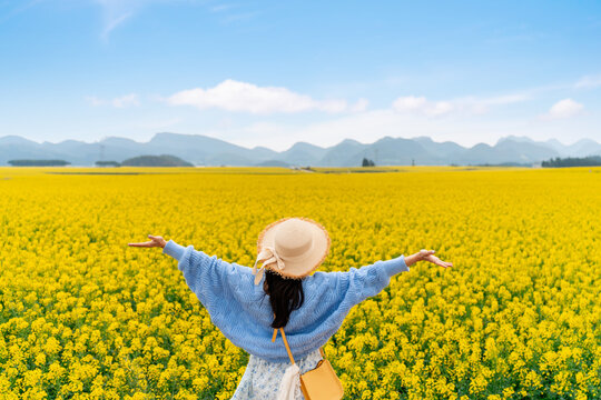Young happy woman tourist enjoying the canola fields while traveling in Luoping, China