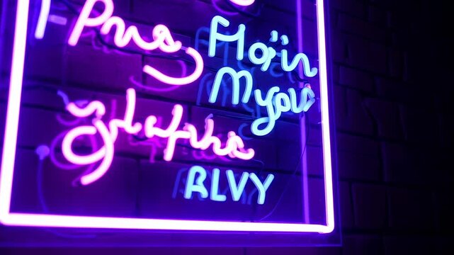 Neon sign with script lettering in vibrant pink and blue hues against a brick wall