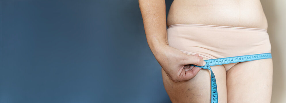 Woman measuring hips with tape for body assessment