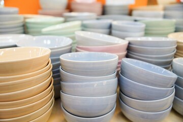 Stacks of ceramic bowls in soft neutral colors neatly arranged, clean kitchenware display with smooth textures and repeating forms for dining and retail use.