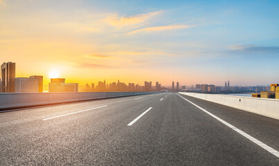 Empty asphalt highway road and city skyline with modern buildings at sunrise in Hangzhou
