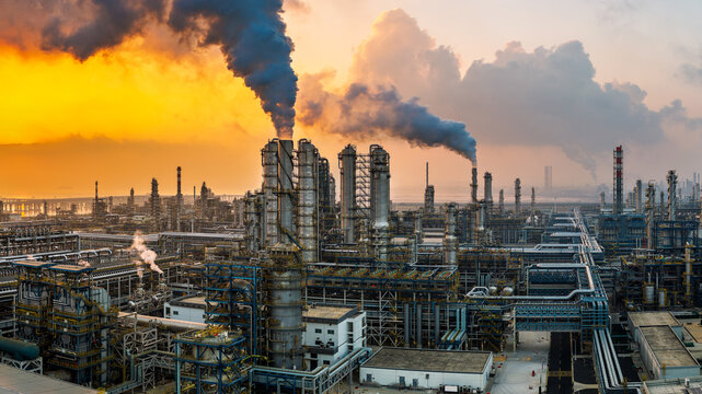 Aerial view of an oil refinery and chemical plant with smoking chimneys at sunset