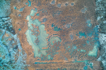 Abstract cracked ice texture with white frost lines and dark water, cold winter nature background, top down aerial drone shot