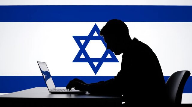 Silhouette of person using laptop in front of flag