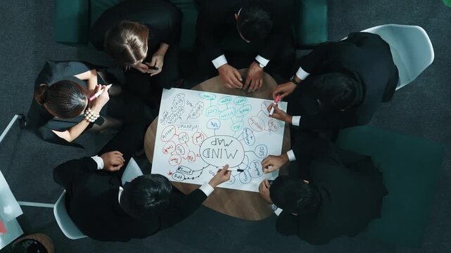 Top down aerial view of people putting hands together and clapping hands to celebrate successful project while using mind map to brainstorm idea. Skilled team stacking hands together. Directorate.