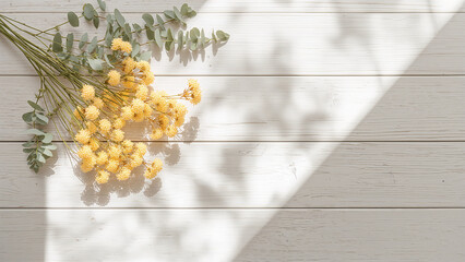 Fototapeta premium 春の午前、窓辺の木製テーブル左上に置いたミモザと木漏れ日の影