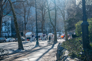 Horse drawn carriages line Central Park South during winter with historic buildings and Manhattan skyline creating a timeless New York street scene