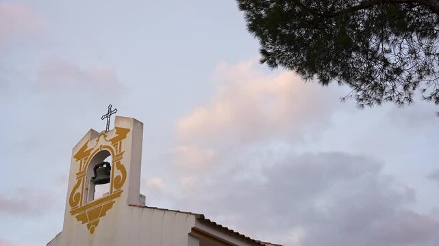 Religious concept. Top of a small church. The cross stands out against the sunset. Super slow motion. 100 fps