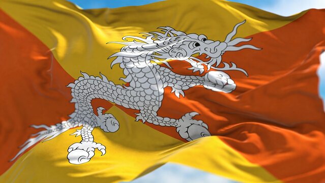 Vibrant Bhutan national flag fluttering in the wind, showcasing a dragon emblem against a bright blue sky. Ideal for cultural presentations or educational materials.