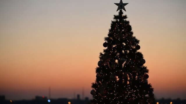 Tall, lit-up Christmas tree against a warm, gradient sunset sky with city silhouette - Powered by Adobe