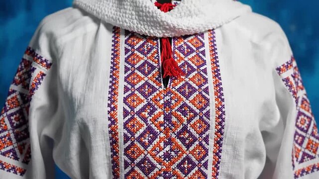 Traditional embroidered white shirt with red and purple patterns on blue background
