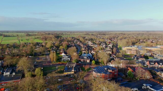 Drone footage moving right over a village and surrounding forest in Eelde, The Netherlands, during winter, capturing houses, trees, and the quiet landscape without snow.
