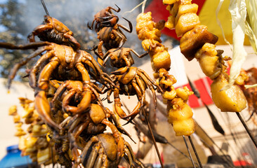 River crabs and pieces of meat are skewered and grilled at a roadside food stall during Magh Bihu celebrations, highlighting traditional Assamese street food prepared for the harvest festival
