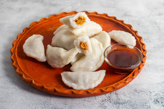 Traditional Bengali bhapa puli pitha is a steamed rice dumpling filled with sweet coconut and jaggery, soft, aromatic, festive delicacy enjoyed during winter celebrations.
