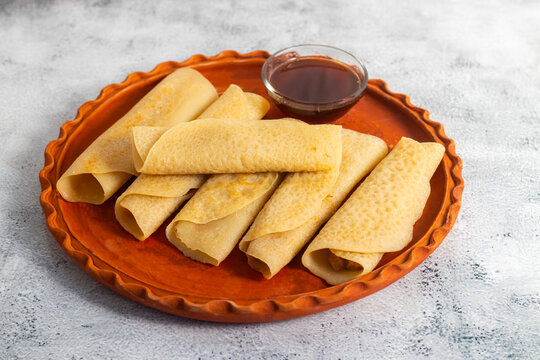 Patishapta Pitha, a Traditional Bengali dessert featuring thin rice flour crepes filled with sweet coconut, jaggery, or khoya, gently folded and served warm during festivals, celebrations, winter.
