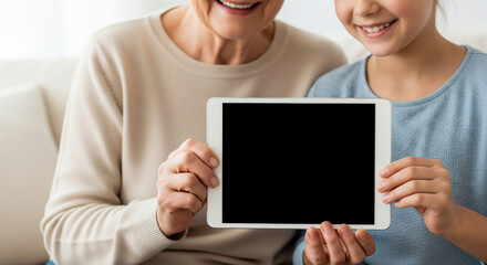 Senior woman and child holding tablet with black mockup screen for healthcare app demo