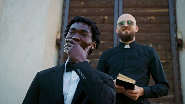 The groom is happy to see the bride for the first time, standing on the church threshold near the priest