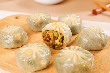 Fototapeta premium Steamed Asian Dumplings with Sautéed Vegetable Filling on Wooden Board
