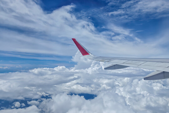 Commercial airplane wing flying above fluffy white clouds over Kota Kinabalu, Malaysia, capturing peaceful aviation travel scene. - Powered by Adobe