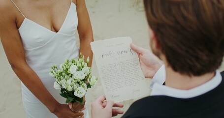 Naklejka premium A sheet with a handwritten vow in the groom's hands at an outdoor wedding