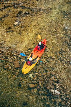 Two kayakers paddle through a crystal-clear river Mostnica in Bohinj, Slovenia - symbolizing outdoor adventure, teamwork, and exploration.