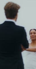 Fototapeta premium The bride and groom are spinning holding hands, and then kissing and hugging standing on the seashore
