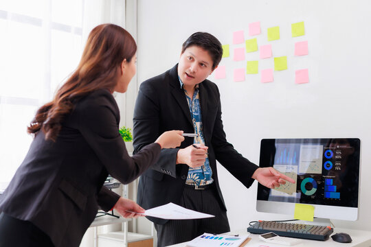 Business colleagues discussing analytics and strategy, pointing at charts on a computer screen in a bright modern office - Powered by Adobe