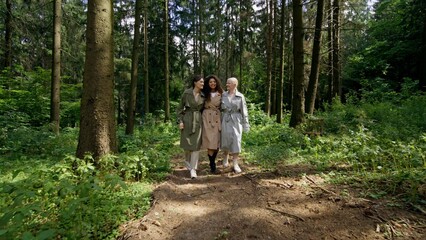 Fototapeta premium Three women with different skin colors are talking while walking in the forest