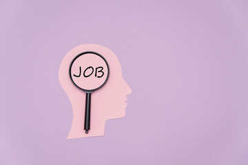 A pink silhouette of a human head with a magnifying glass highlighting the word 'JOB'. The background is a soft purple color, emphasizing the theme of job searching.