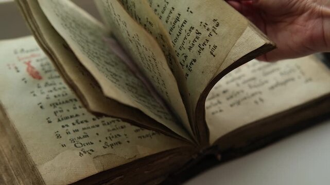 Turning through pages of Slavic Gospel, old pages with candle wax stains, Orthodox holy Bible for Christians, psalter with psalms. Cyrillic Church Slavonic. 