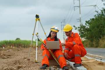 A male and female architect are inspecting the completeness of the road construction at the wind turbine farm.