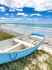 Fototapeta premium Small rowboat dinghy on a beach beneath beautiful blue azure sky