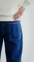 A man puts his hands in the back pockets of his jeans, vertical