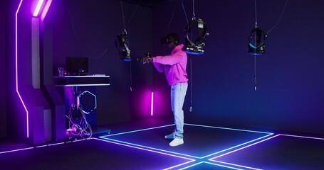 A man with a virtual reality headset plays an online game using joysticks