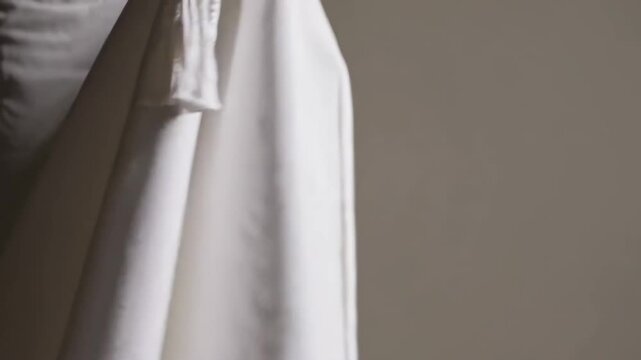 Hands fold a white prayer shawl with care, highlighting texture, respect, and tradition.