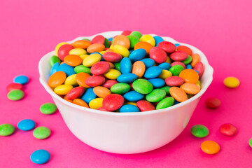 Multicolored candies in a bowl on a colored background. birthday and holiday concept. Top view with copy space