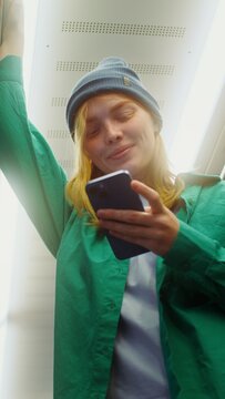 Woman smiles using smartphone in subway car