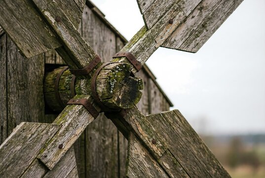 Old weathered wooden windmill blades close up. Rustic traditional gristmill architecture. Rural farm structure with aged timber texture.